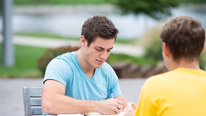 两个学生在户外的桌子上学习.